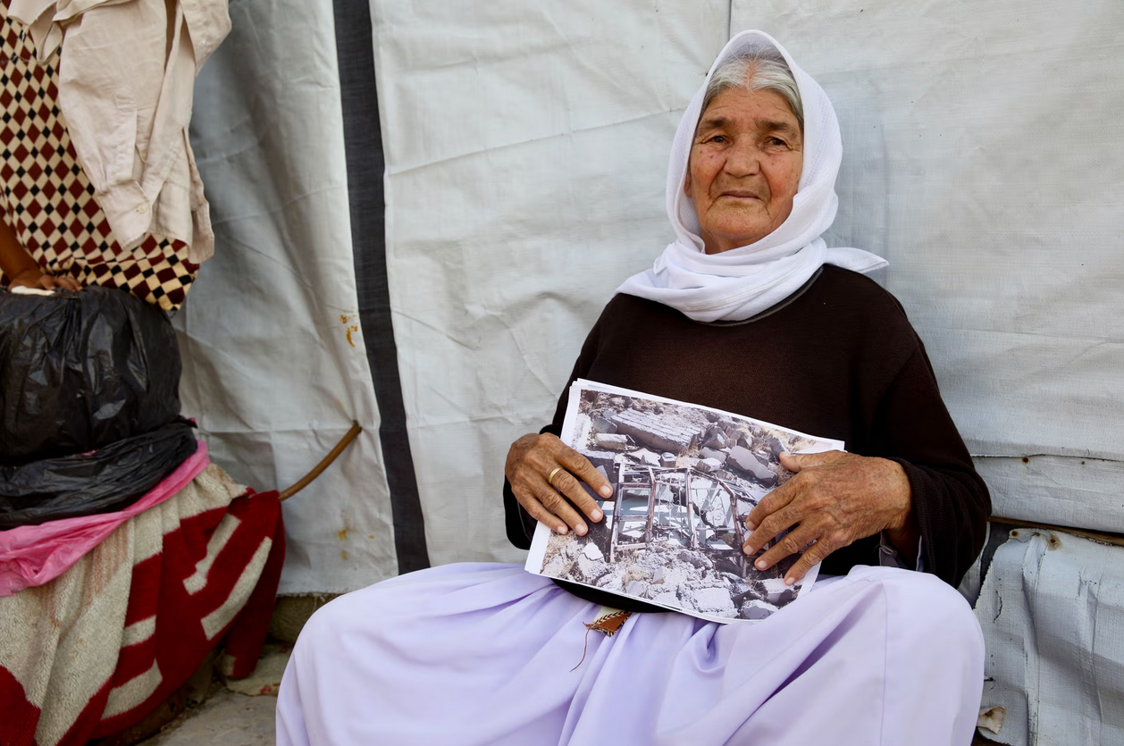 Вынужденная бежать от Исламского государства (ранее ИГИЛ), Джони Шебо Али Амер, в лагере Шария, держит фотографию своего разрушенного дома в Синджаре. "Нам некуда идти", - говорит она. Фото: G Ligios