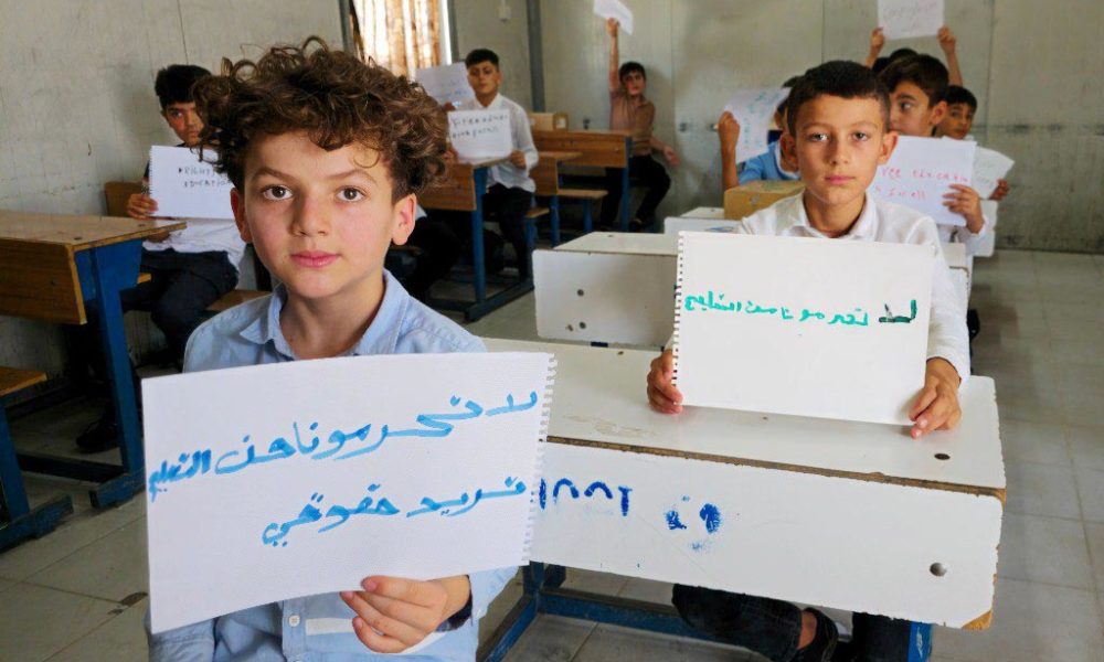 В начале ученик начальной школы Саид Хаджи Хама держит листок бумаги с надписью «Не лишайте нас образования». Фото: Аммар Азиз